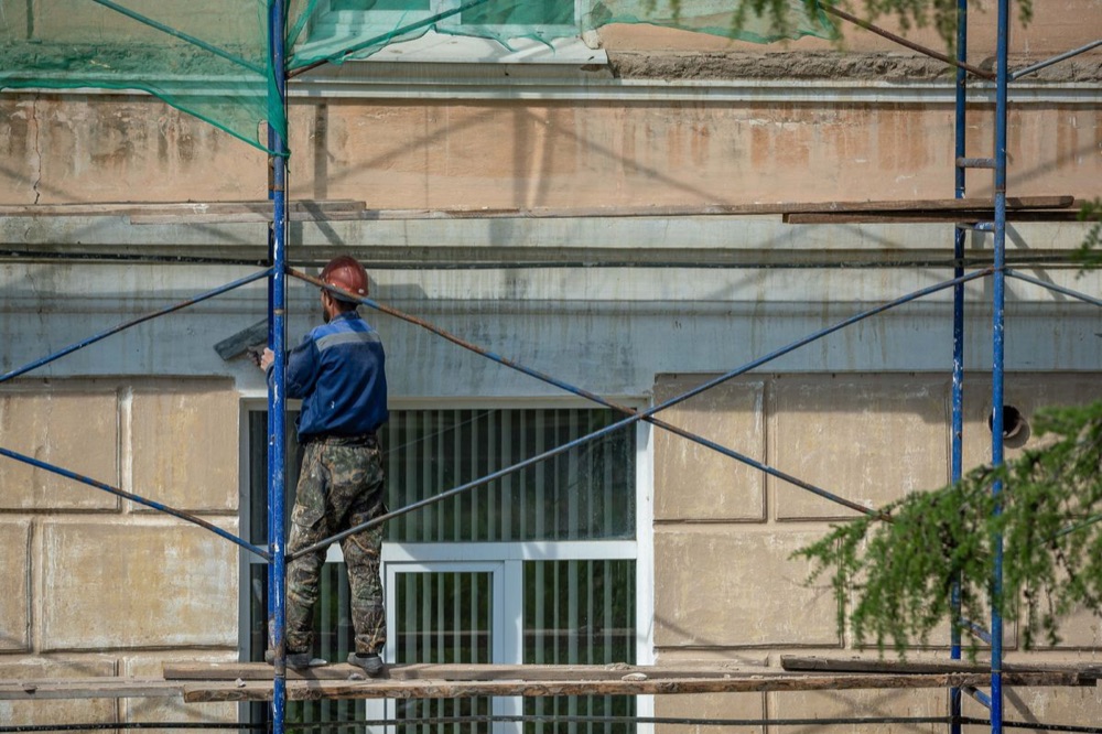 Работник санира фасада на скеле